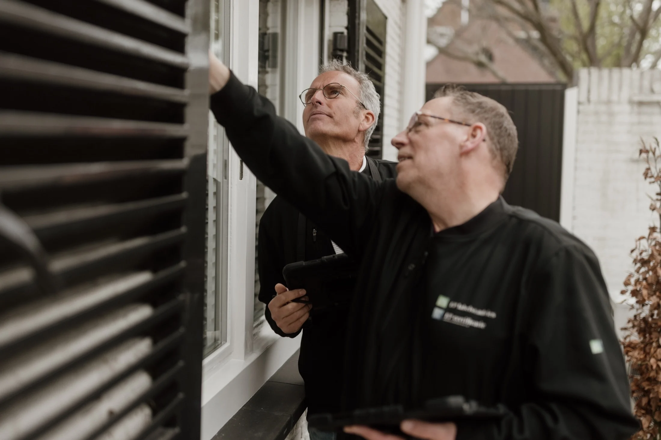 Twee mensen met tablets bekijken samen een raam van een woning